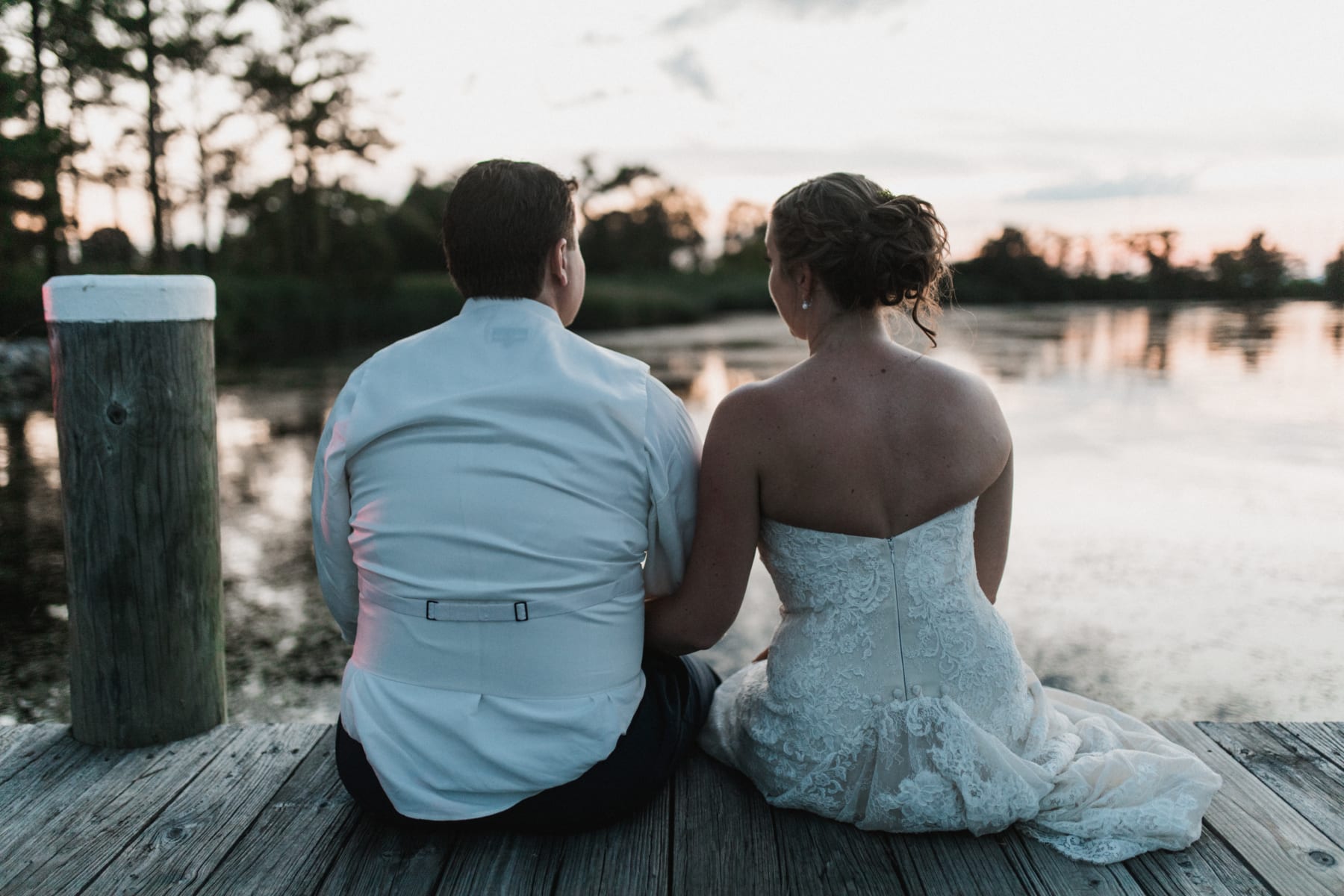 Wedding couple sitting on dock.