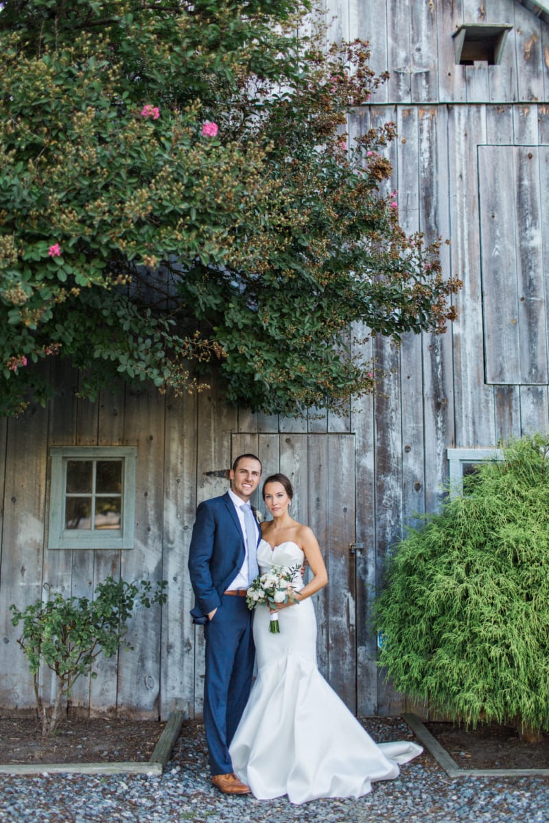 Wedding couple posing for image in front of barn.